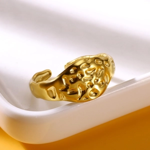 Macro detail of gold hammered texture open ring on a ceramic tray for adjustable fit