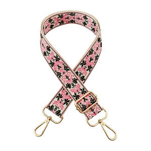 Detail of adjustable beige guitar strap with pink floral embroidery and gold metal clasps