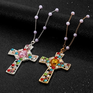 Close-up of gold and silver cross necklaces with tassels and lavender pearls