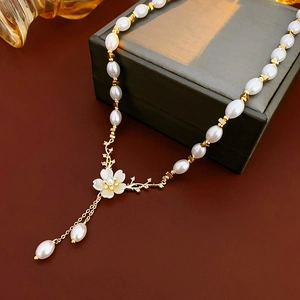 Détail d'un collier de perles avec fleurs et glands en zircon sur un écrin de luxe