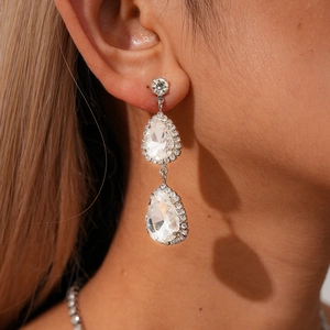 Vue détaillée de boucles d'oreilles argentées en forme de larme avec zircons sur un modèle