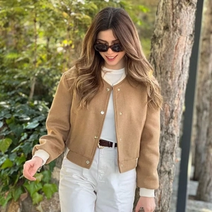 Detail of camel cropped pilot jacket with white ribbed cuffs and metal button accents