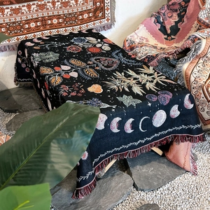 Detail of woven camping blanket with moon phase patterns and decorative fringe trim