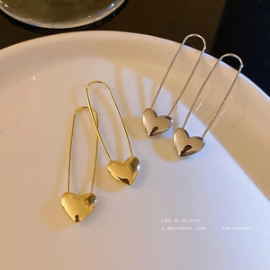 Macro shot of polished heart-shaped safety pin earrings in gold and silver finishes