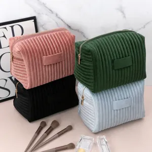 Close-up of four soft velvet toiletry bags with quilted patterns and gold metal zippers
