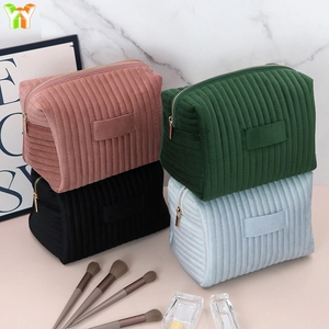 Close-up of four soft velvet toiletry bags with quilted patterns and gold metal zippers