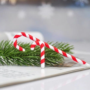 Red and white striped Christmas candy cane ornaments set on festive pine needles