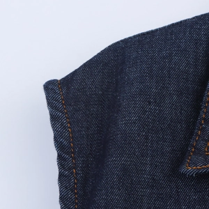 Gros plan détaillé du denim bleu foncé avec double surpiqûre orange sur l'épaule de robe