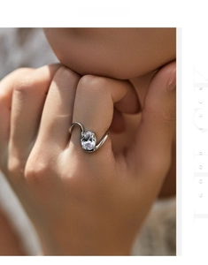 Detailed view of an S-shaped silver ring featuring a large oval-cut sparkling gemstone