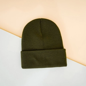 Flat lay of olive green ribbed knit beanie with Leave Me Alone embroidery detail