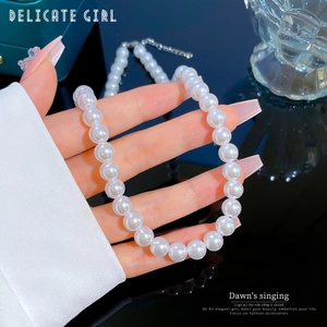 Détail d'un collier de perles blanches brillantes tenu à la main sur fond sombre luxueux