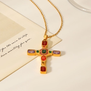 Macro shot of gold cross pendant necklace featuring inlaid multi-colored cubic zirconia stones