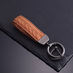 Brown braided suede car keychain with gunmetal grey buckle on black stone background