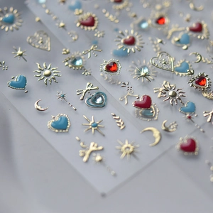 Close-up of gold nail stickers with heart, moon, and sun patterns with inlaid gems