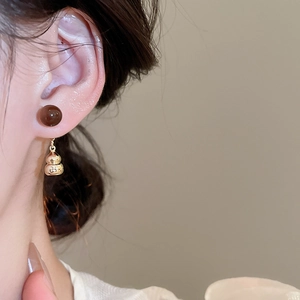Close-up of vintage tiger eye stone gourd pendant earrings on a female model