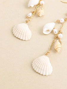 Macro shot of seashell and pearl pendant detail on gold chain bohemian earrings