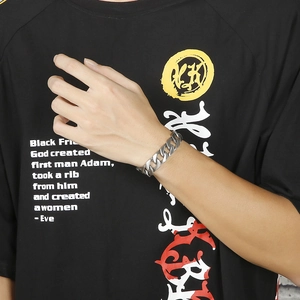 Close-up of polished silver Cuban link bracelet worn on a wrist with a black streetwear tee