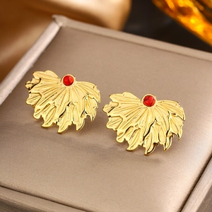 Macro detail of 18K gold plated feather fan earrings with red stone inlay on jewelry box