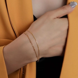 Close-up of a double-layered gold snake chain bracelet with bead details on a female wrist