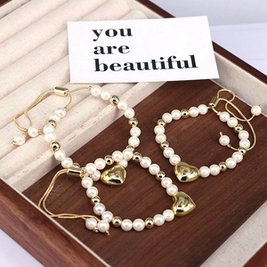 Elegant adjustable beaded pearl bracelets with gold heart charms on a wooden tray
