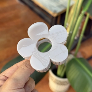 Détail de la pince à cheveux fleur blanc cassé avec finition brillante et ressort doré
