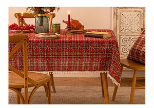 Close-up of red plaid Christmas tablecloth with white snowflake dots and tassel trim