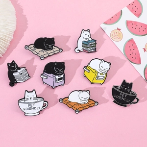 Detail showing various cute cartoon cat enamel pins including a cat on a pile of books