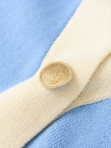 Close-up of sky blue knit fabric with a vintage embossed gold button detail