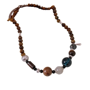 Ethnic style necklace with tiger eye stones, wooden beads, and a silver pendant on white background