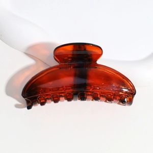 Detailed view of an amber semi-circle hair claw clip with a glossy finish
