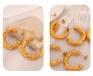 Detailed close-up of gold C-shaped earrings with hammered and striped metal textures
