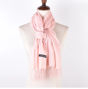 Detail view of pink cashmere scarf featuring elegant fringes and a black brand label
