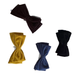 Set of four velvet bow hair clips in brown, yellow, blue, and black colors on white background