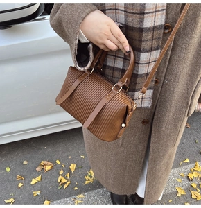 Nahaufnahme der braunen Plissee-Boston-Tasche mit Gurt und goldenen Metallhaken