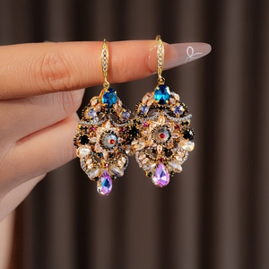 Detail of vintage palace style gold earrings with multicolor teardrop crystals on a model