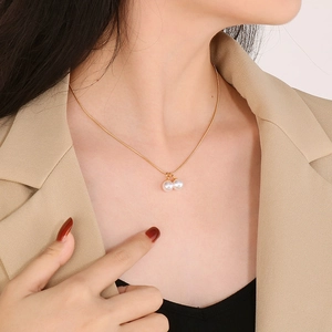 Primo piano della collana a catena serpente dorata con due pendenti in perla bianca