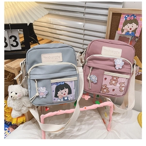 Détail de jolis sacs bandoulière en toile bleu et rose avec des breloques brodées