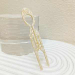 Macro shot of cream cellulose acetate U-shaped hair fork with elegant marble texture