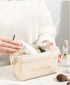 Dettaglio della borsa trucco cloud color crema con ampia apertura e scritta elegante