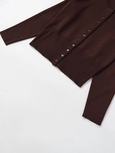 Detail of chocolate brown knit cardigan featuring ribbed hem and matching round buttons