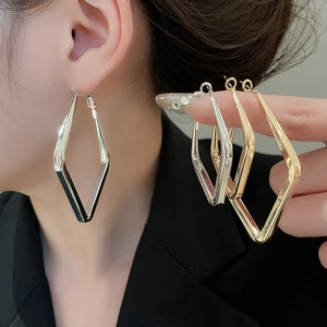 Detailed view of geometric rhombus metal hoop earrings in gold and silver finishes