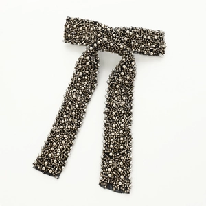 Macro detail of handmade beaded bow hair clip with vintage metallic beads on mesh