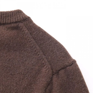 Detailansicht des gerippten Rundhalsausschnitts und der Textur der braunen Strickjacke