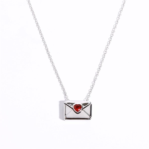 Macro shot of silver envelope locket with a red heart gem and delicate chain