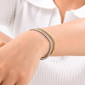 Detail of layered gold and silver beaded bracelets on a woman's wrist in a stylish pose