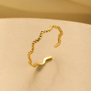 Close-up of wavy gold-plated stainless steel open bracelet with textured finish
