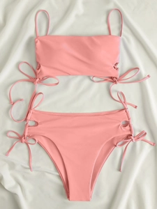 Detail of coral pink bikini set featuring side hollow cut-outs and bow tie accents