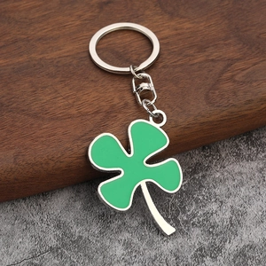 Green lucky four-leaf clover keychain with silver metal ring on textured background