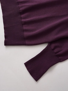 Dettaglio ravvicinato dei polsini e dell'orlo del maglione in maglia viola scuro a coste
