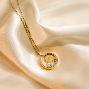 Golden Evil Eye coin pendant necklace on beige silk fabric background for women
